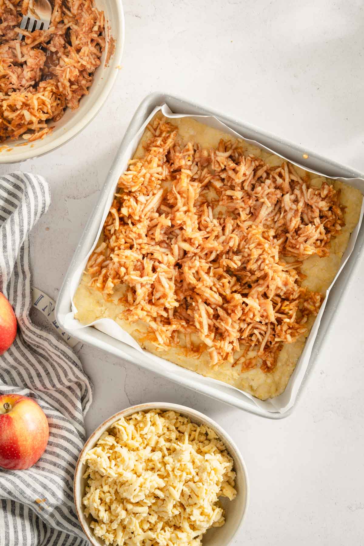 baking pan with dough and shredded apples layered on top