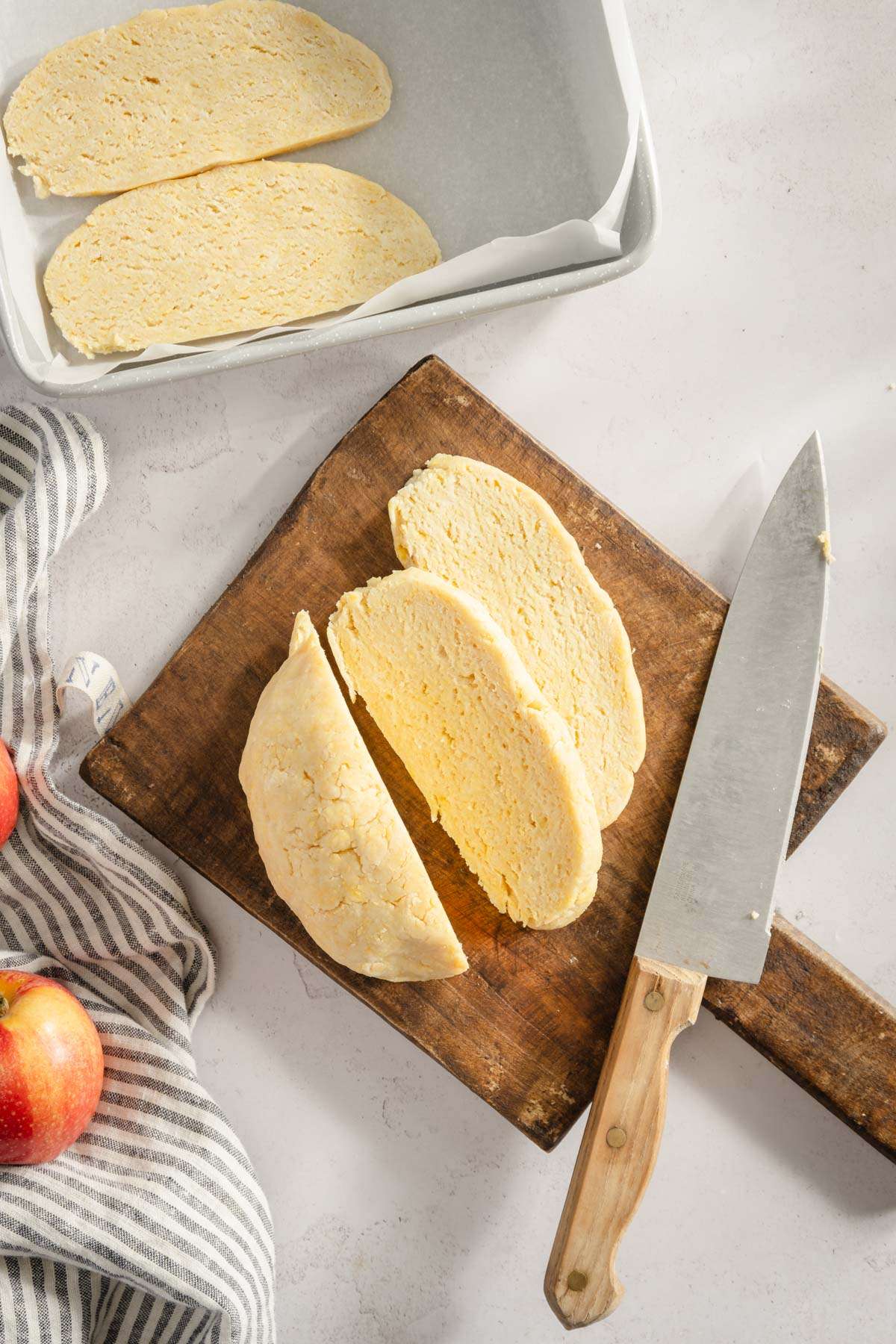 dough on a cutting board cut into slices, baking dish with slices of dough in it