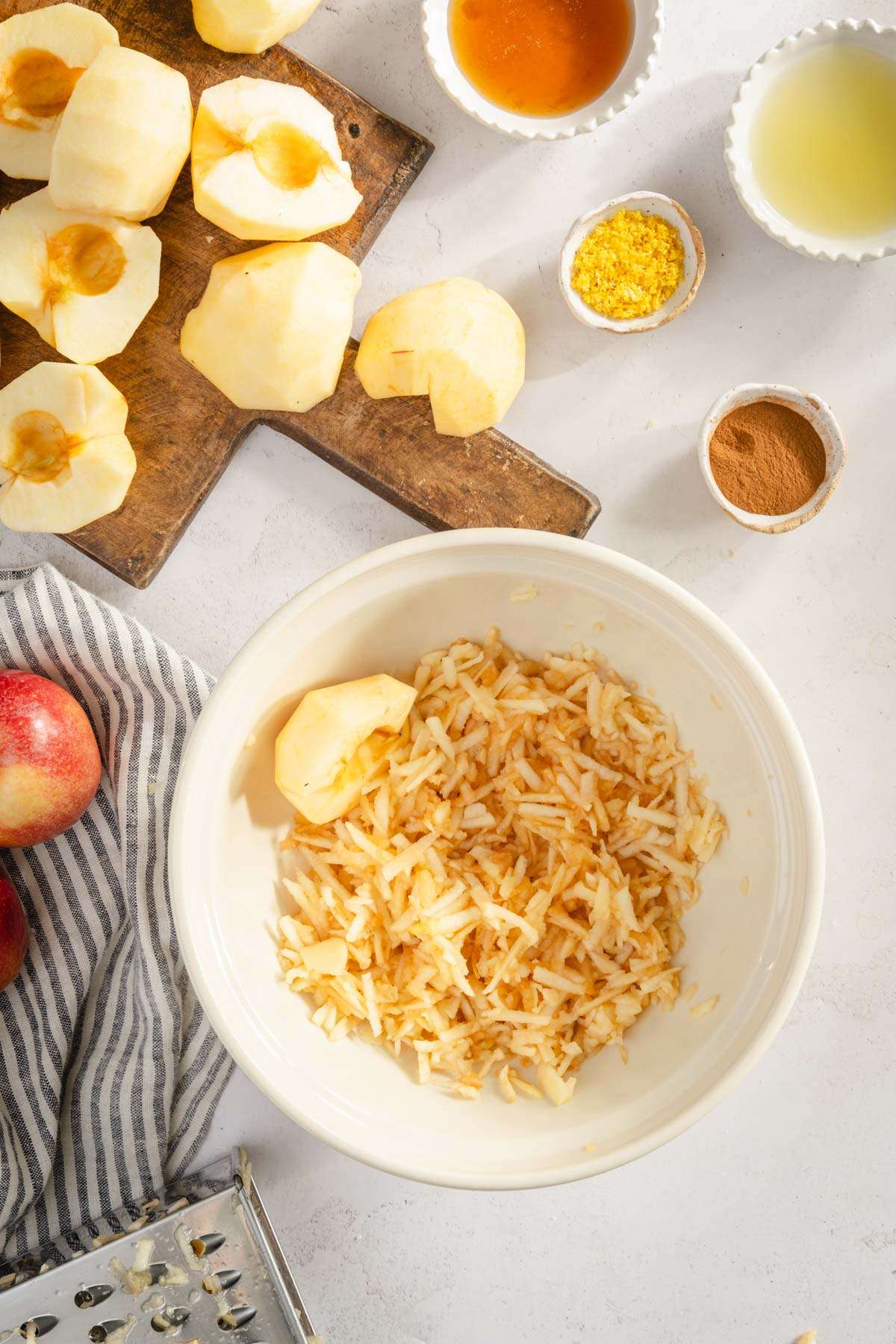 peeled and cut apples, some shredded in the bowl, napkin