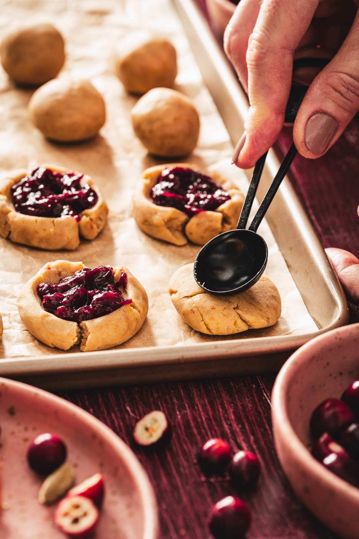 hands in frame holding teaspoon and shaping the cookie dough