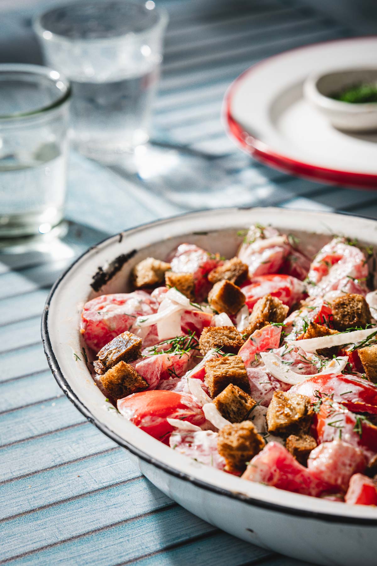 tomato salad in a serving dish, glasses with water