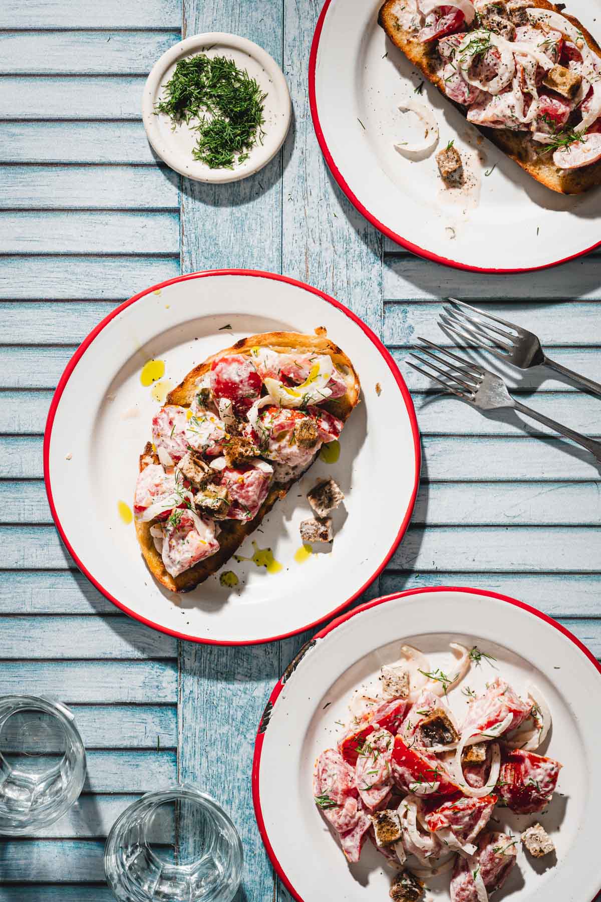 three plates with toasted bread topped with the salad