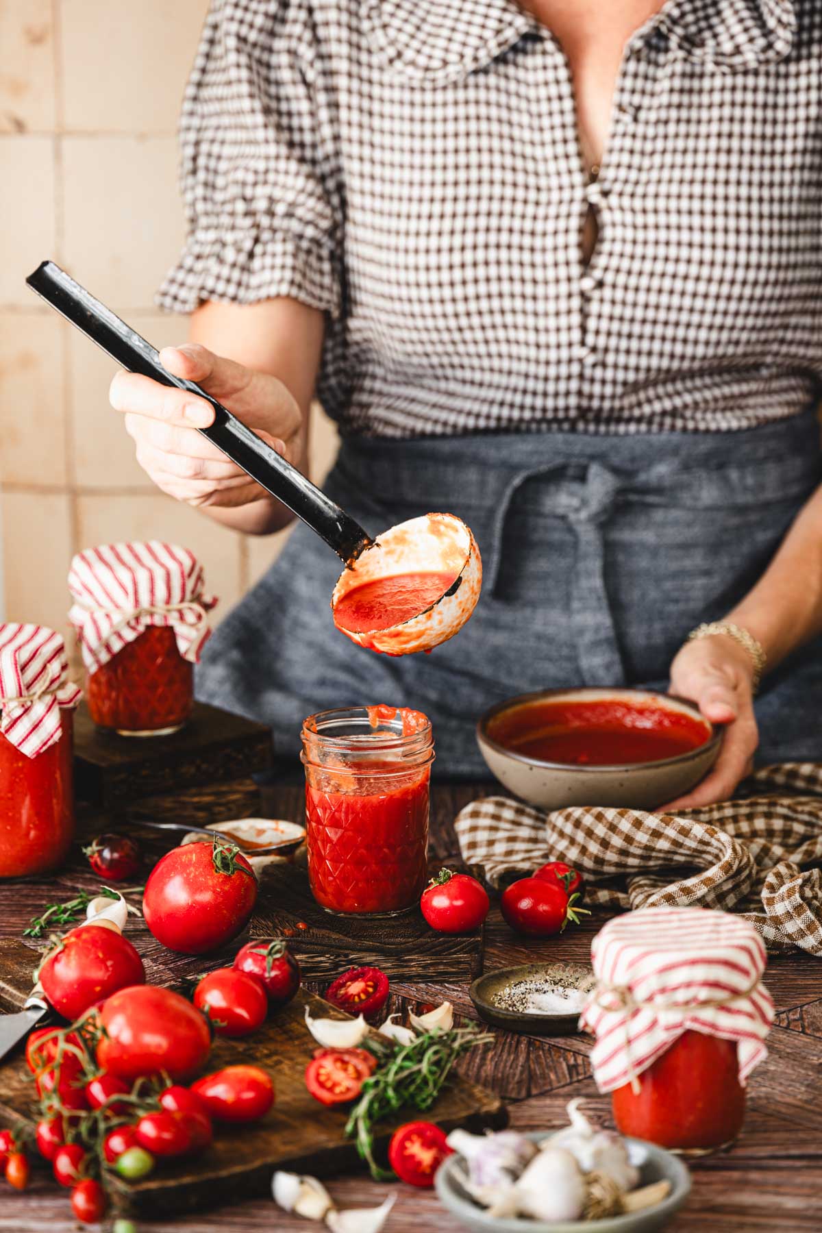 hands in frame holding a ladle with tomato sauce