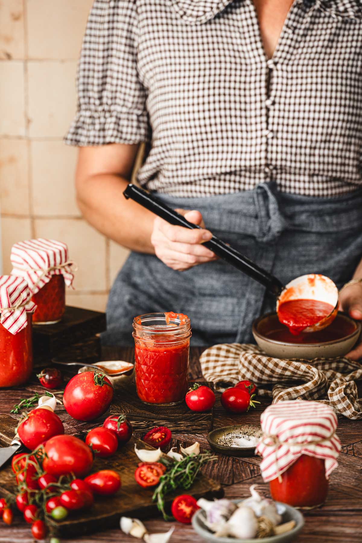 hands in frame holding a ladle with tomato sauce