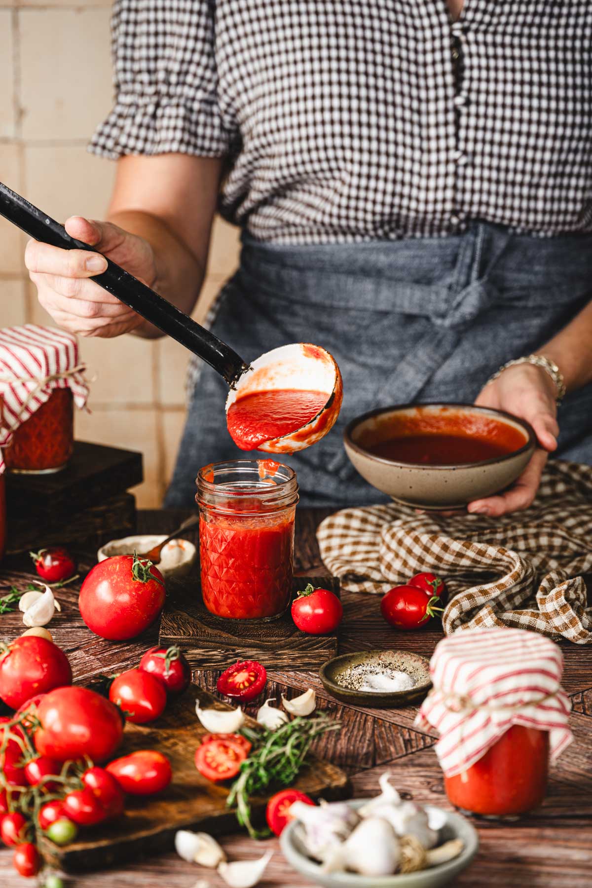 hands in frame holding a ladle with tomato sauce