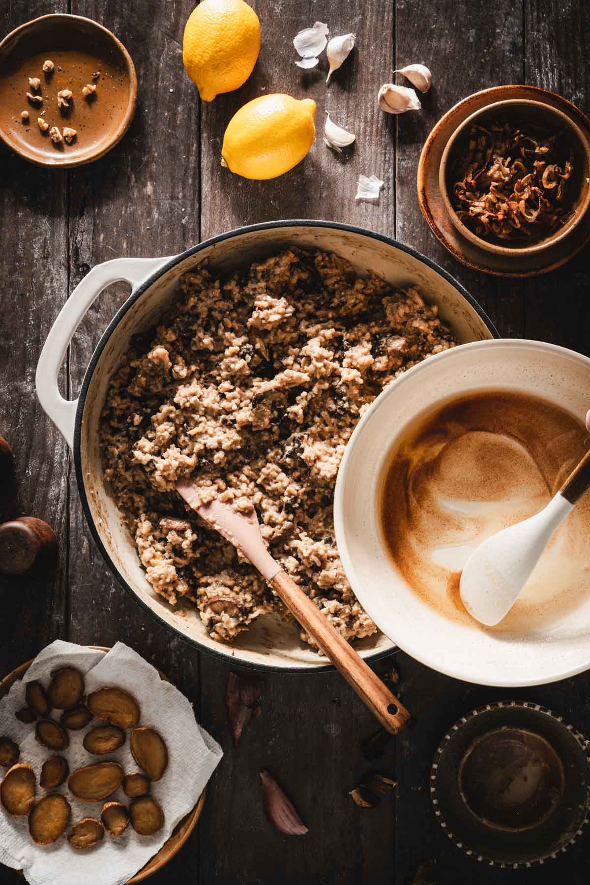hands in frame pouring brownd butter into the pan with the risotto