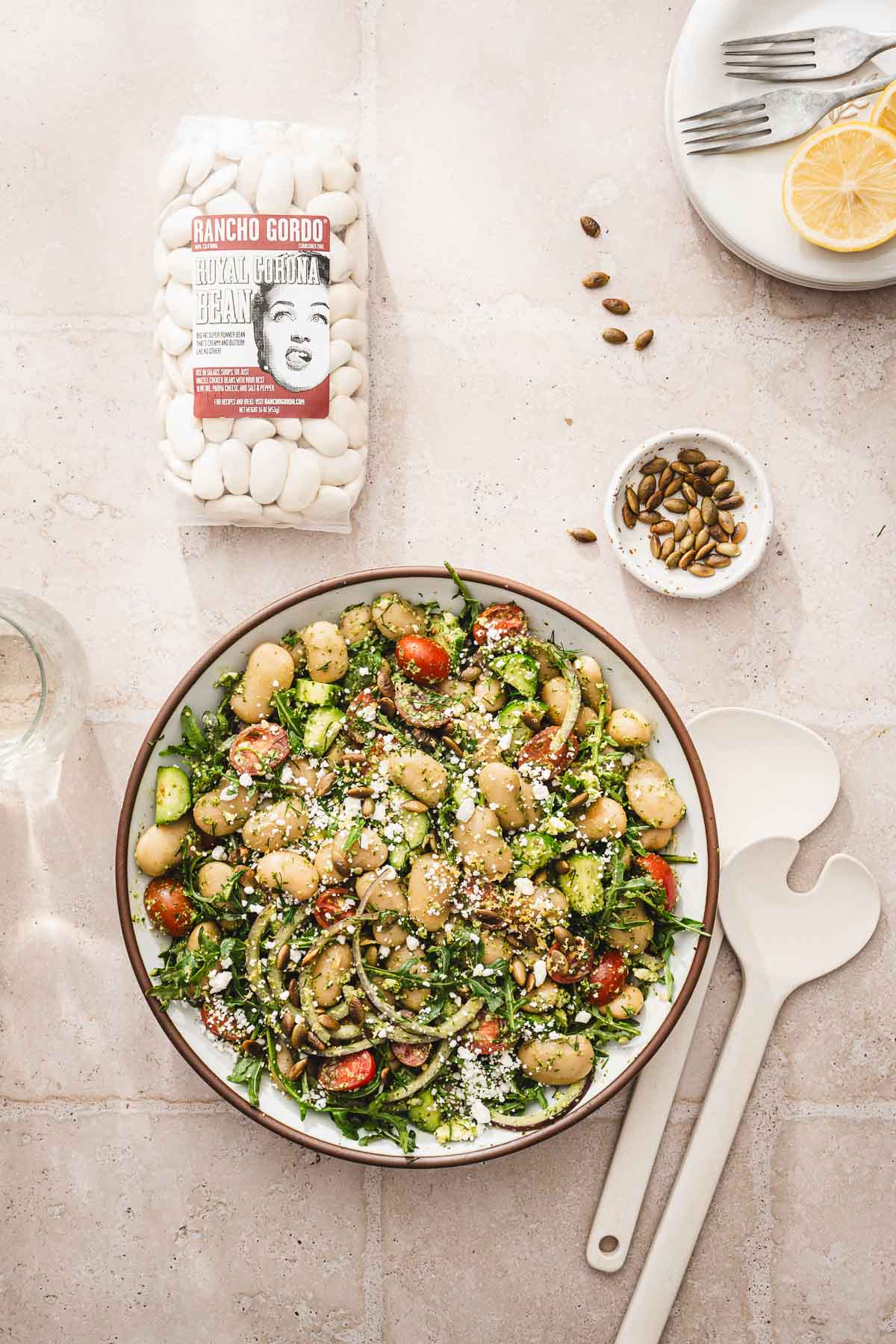 bowl with salad, bag with dry beans, dish with pumpkin seeds