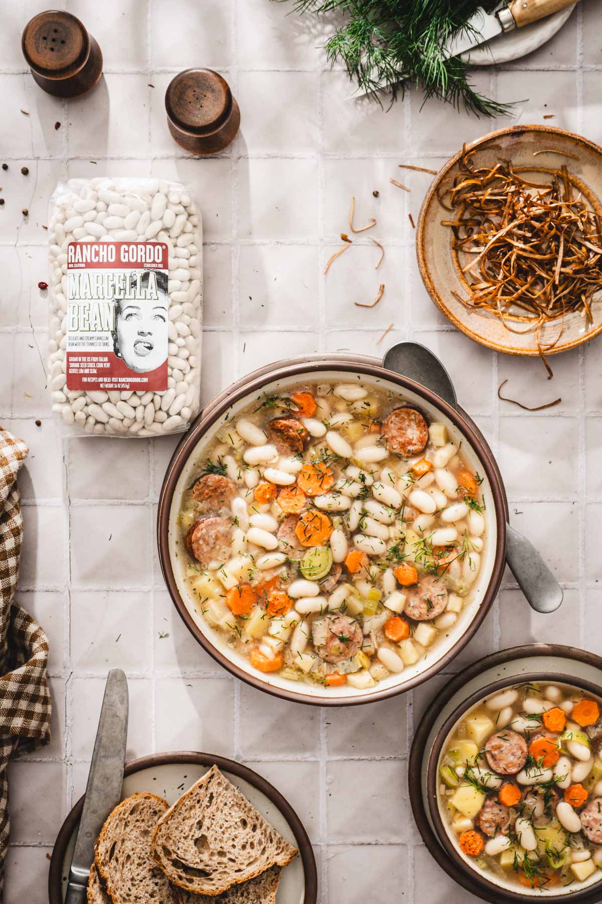 bowl with the soup, bag with dry beans, plate with fried leeks, salt and pepper