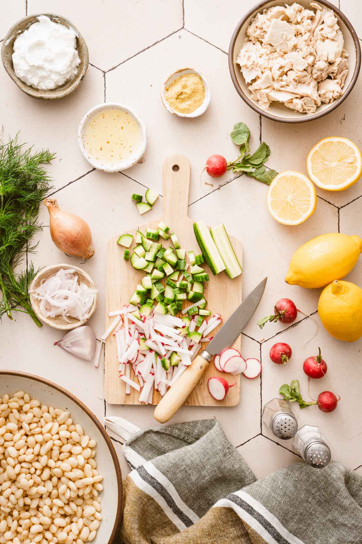 wooden cutting board with chopped cucumbers and radishes