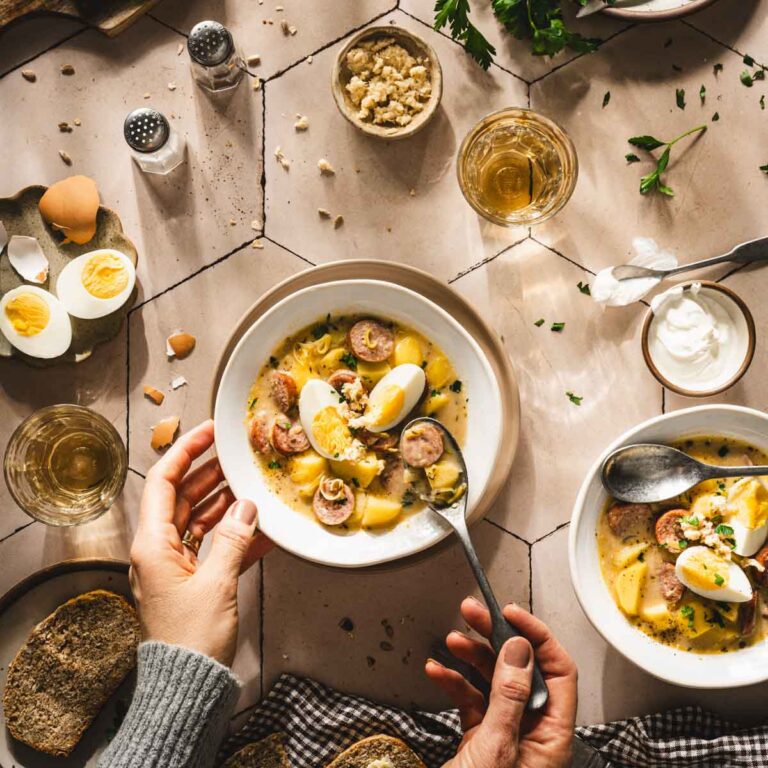 hands in frame holding spoon over bowl with soup
