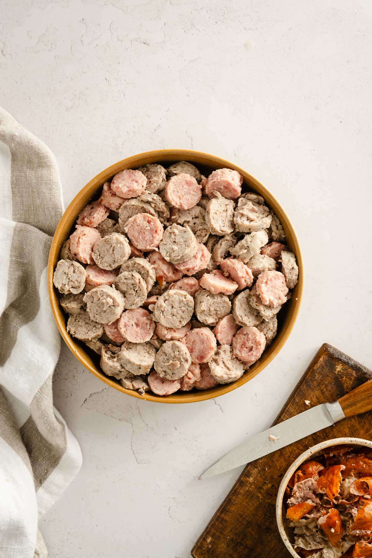 dish with cut up sausages, cutting board with knife