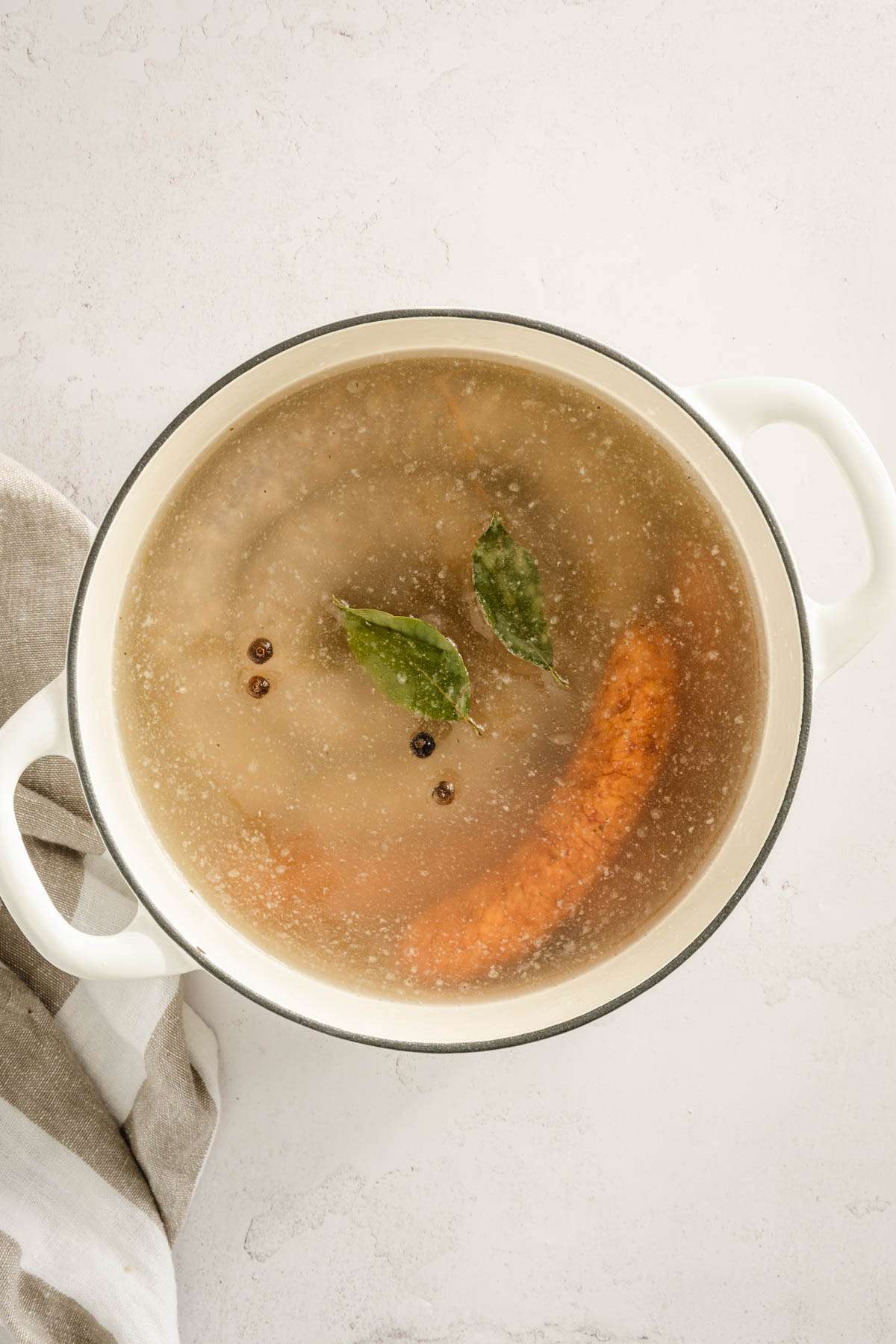 stock pot with sausages and broth together, bay leaves and allspice added to the pot