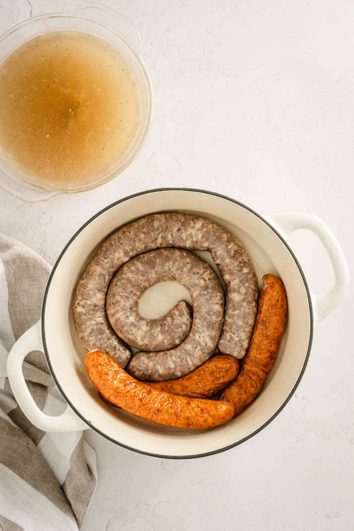 sausages in a stock pot, bowl with broth to the side