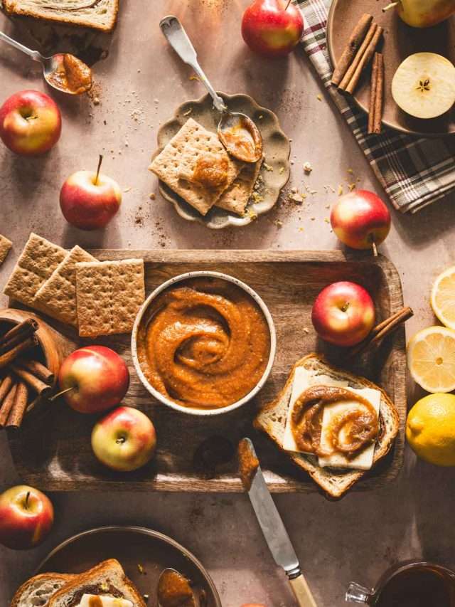 apple butter on a serving board, fresh apples, cinnamon sticks, slices of bread