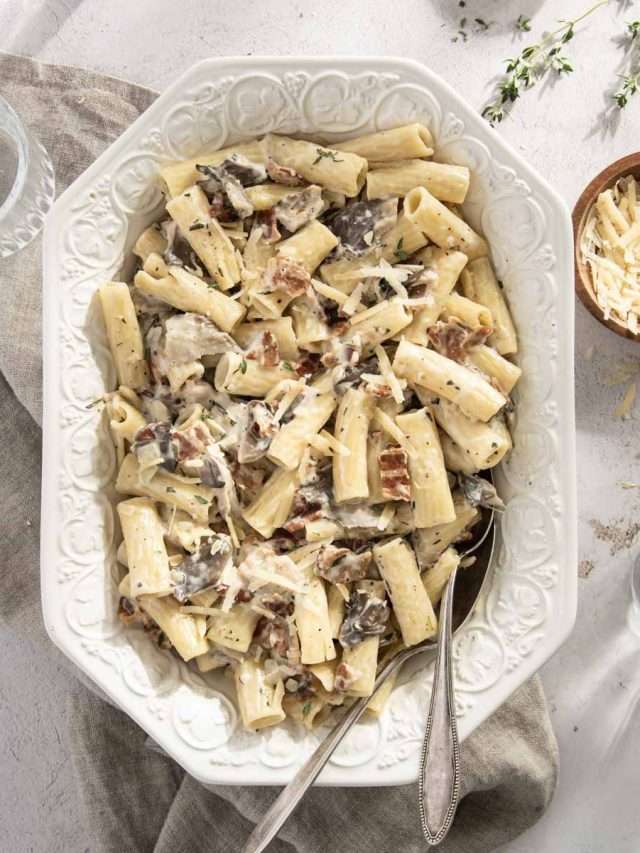 pasta in a serving dish, small bowl with shredded parmesan cheese