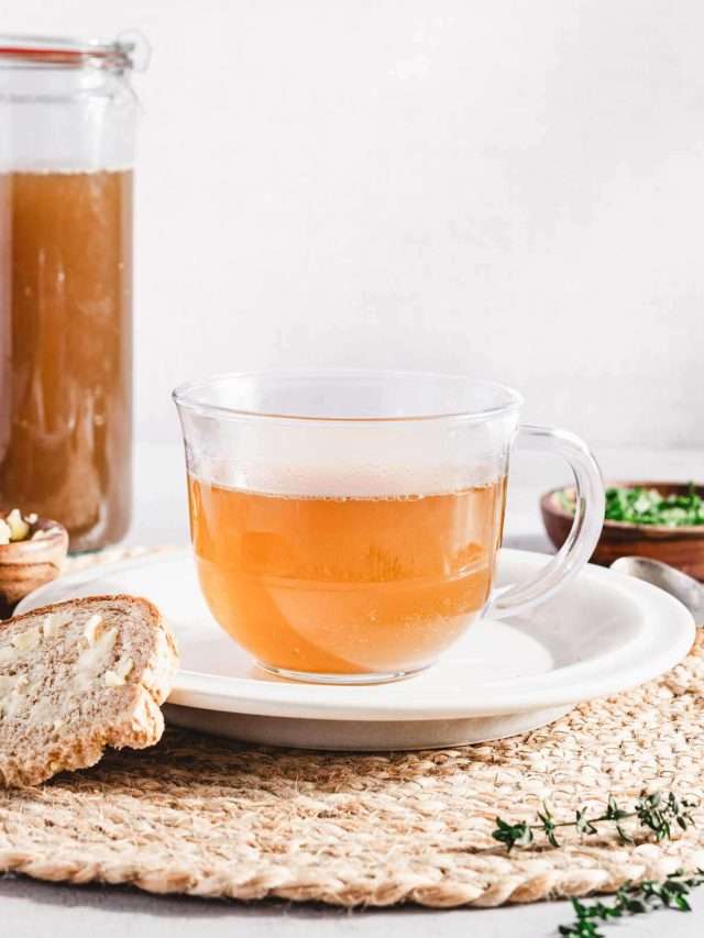 beef broth in a drinking glass, slice of bread, dish with chopped parsley