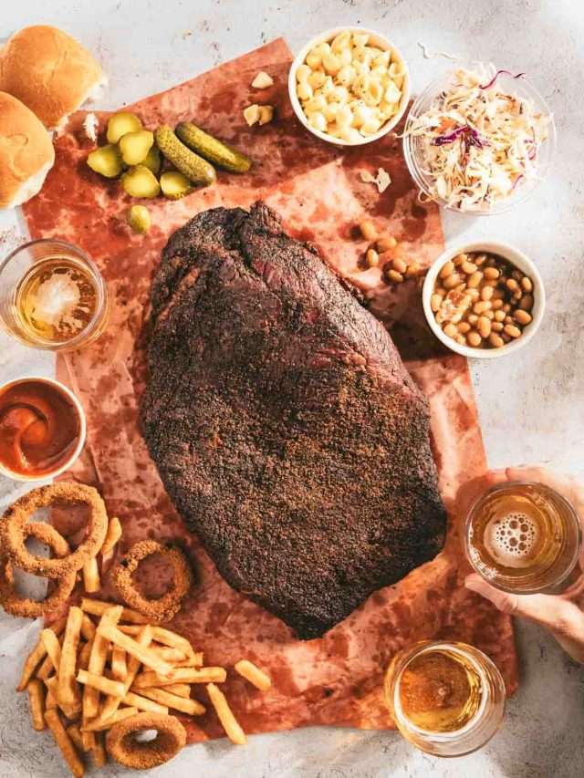 whole smoked brisket on a butcher paper, side dished around, glass with beer