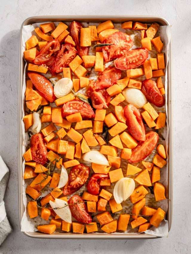 roasted tomatoes, butternut, onions and herbs on a baking sheet