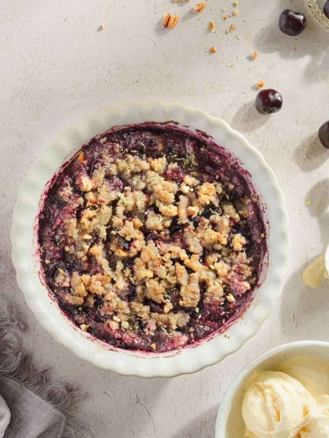 baked cherry crisp shown in a serving dish; light background