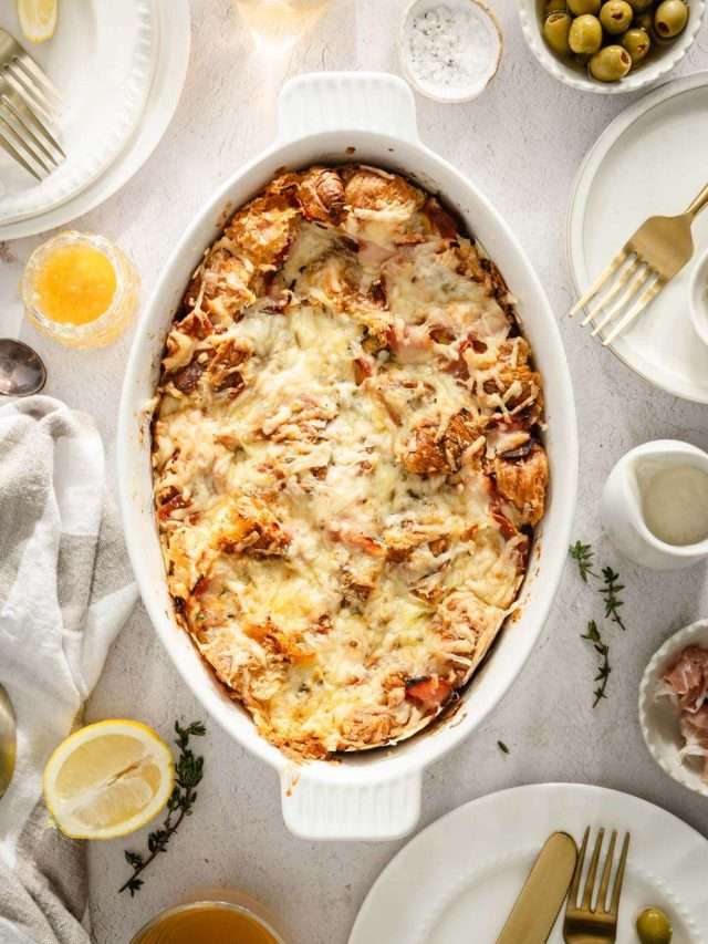 Croissant Bake in a serving dish, plates around, utensils, dish with honey, ham and sauce, glasses with tea