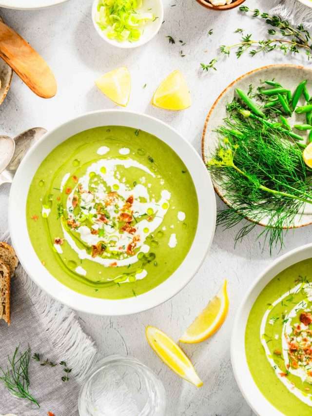 bowl with fava bean soup, garnished with cream, feta cheese and pieces of prosciutto; lemon wedges, plate with fresh dill and chives