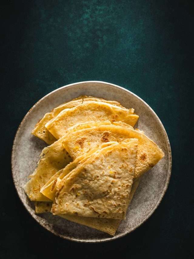 folded nalesniki on a plate, dark green background