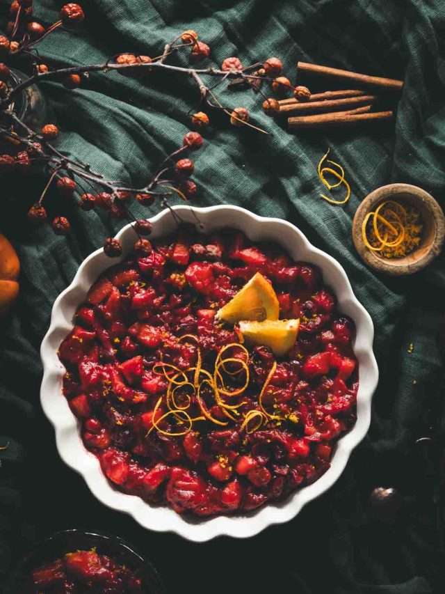 BOWL WITH CRANBERRY SAUCE, SLICES AND RIND OF ORANGES; GREEN BACKGROUND