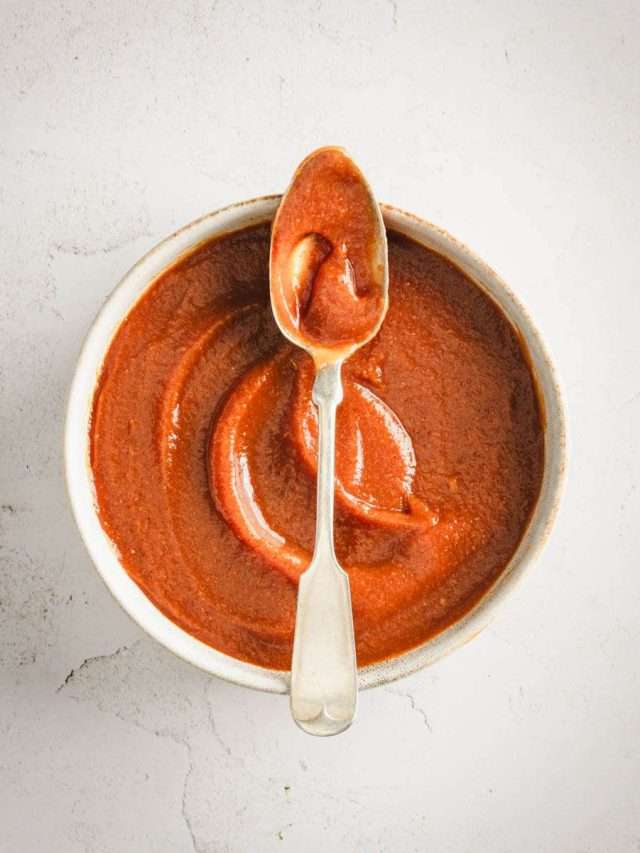 Peach BBQ Sauce in a serving bowl with a spoon placed across the rim of the bowl