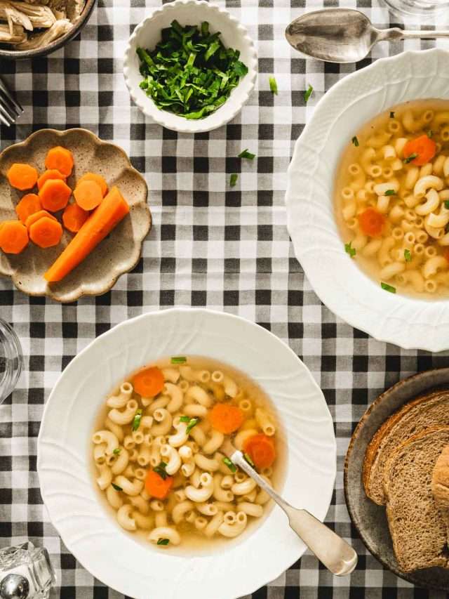table set up, soup plates with rosol, small dish with carrots, bread in a basket, plate with shredded chicken
